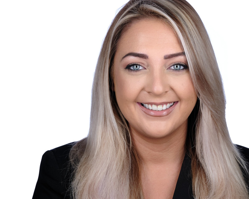 Alanna looks to the camera with a broad smile, wearing a black jacket.